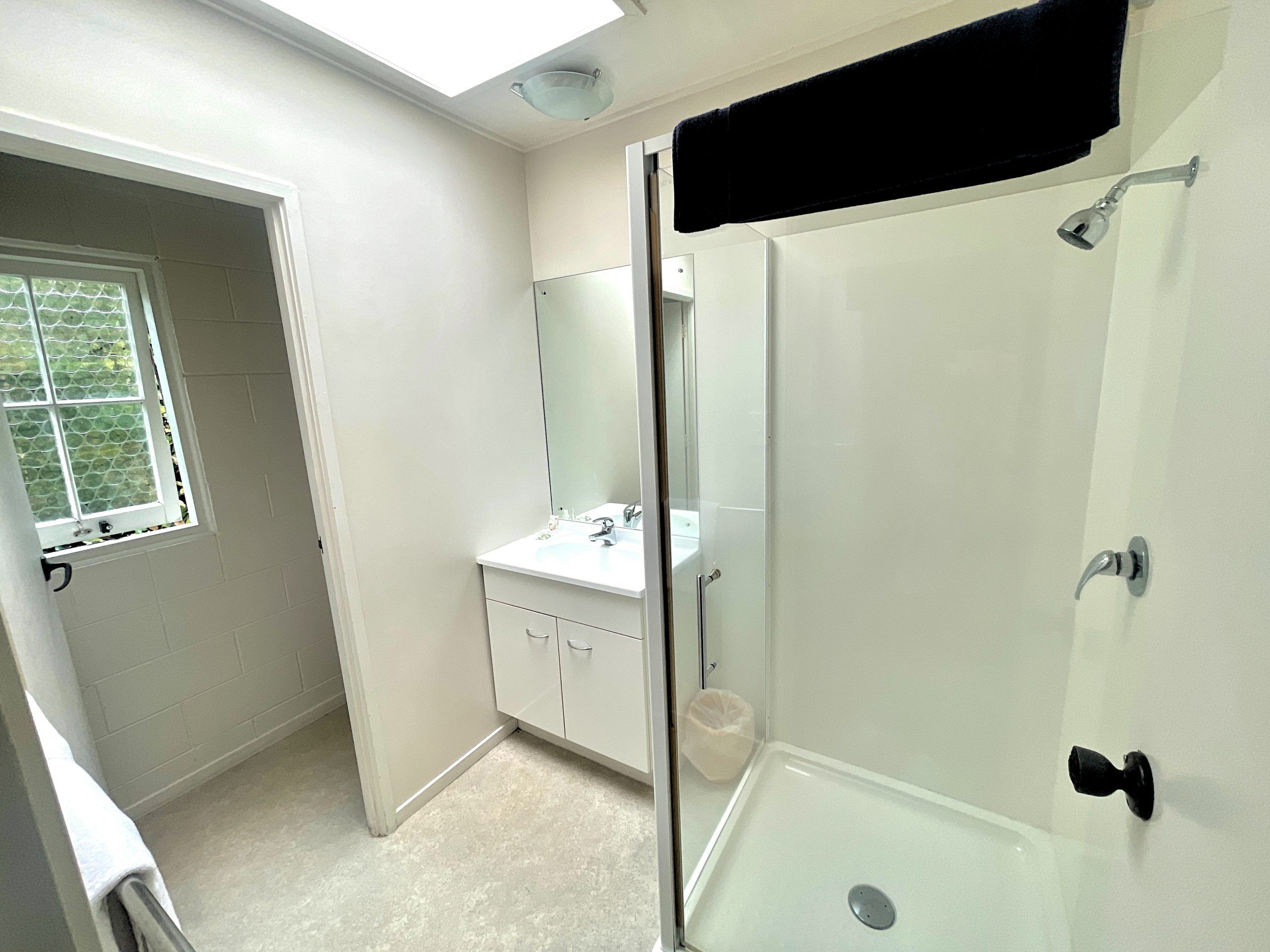 One-bedroom unit bathroom with shower and vanity at Browns Bay Olive Tree Motel