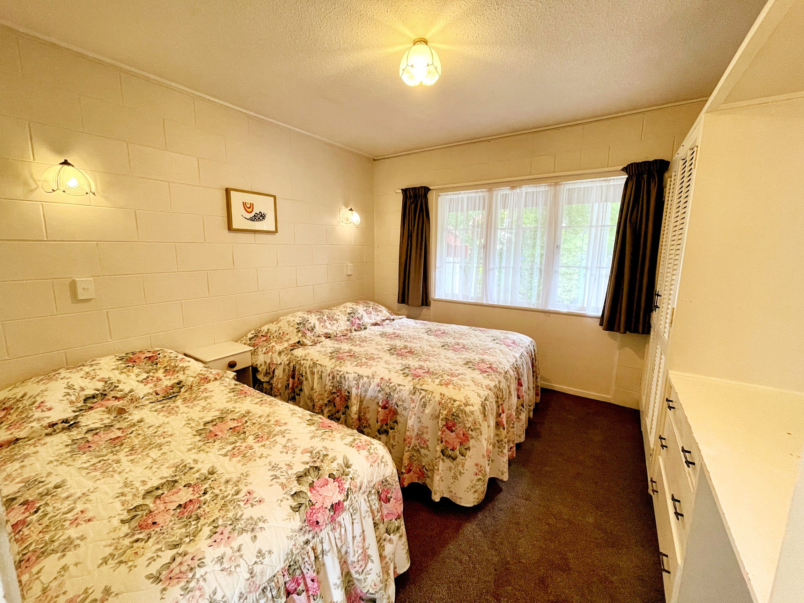 One-bedroom unit bedroom with queen and single beds at Browns Bay Olive Tree Motel